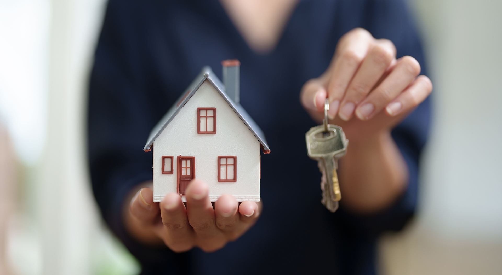 woman holding small home with a key